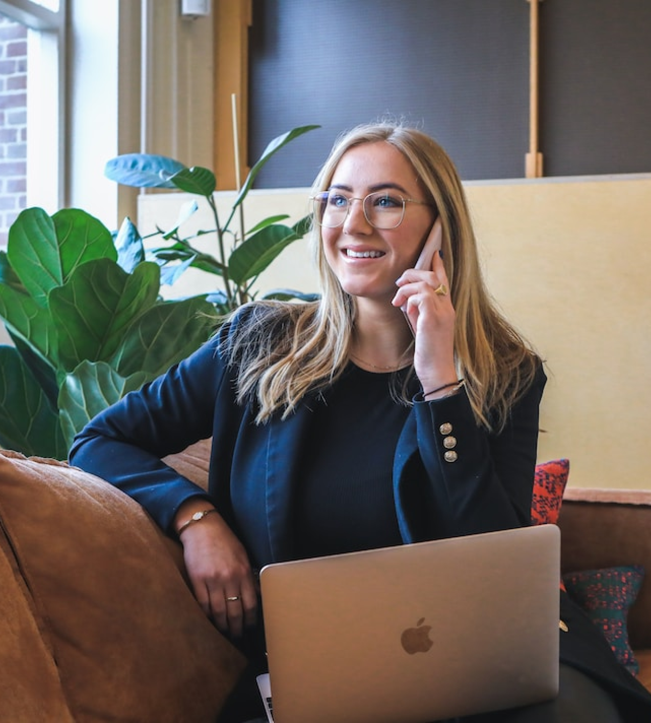 Woman taking a call while holding laptop is on her lap